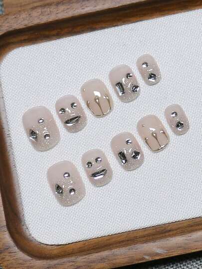 10片纯手工制作的按压式美甲片，短款椭圆形，以透明裸粉为底，融合银色闪粉、手绘液态金属质感和独特形状的钻石，呈现出酷炫精致的造型。温柔优雅的可爱美甲，适合女士和女孩在春夏秋冬的各种节日派对和日常生活中使用。