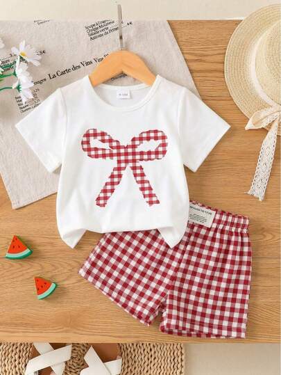 Bộ đồ đôi cho bé gái gồm áo thun ngắn tay in nơ và quần short kẻ caro, chất liệu nhẹ, thích hợp mặc hàng ngày vào mùa hè.