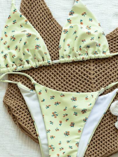 QKJ Bộ bikini tam giác họa tiết hoa nhí, cổ yếm buộc dây sau lưng, dây đeo có thể điều chỉnh, chất liệu co giãn mềm mại, chi tiết nhún bèo ở cúp ngực, mút đệm có thể tháo rời, cổ chữ V sâu, độ che phủ tối thiểu giúp tôn dáng vòng một. Màu kem chủ đạo, kết hợp với quần bikini cùng màu, cạp thấp, thiết kế cắt cao ở phần chân, dây buộc bên hông mỏng, có thể điều chỉnh độ vừa vặn, chi tiết nơ nhỏ tinh tế ở bên hông. Thích hợp cho kỳ nghỉ hè trên bãi biển.