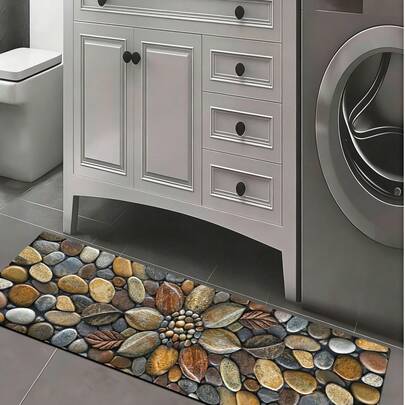 1 tấm thảm bếp bằng gel silica với thiết kế in hình sỏi 3D siêu thực, nền màu xám đậm với các viên sỏi tròn nhiều màu nâu, vàng, xám, trắng, tạo cảm giác tự nhiên và sang trọng, thảm bếp êm ái chống mỏi, bề mặt vải thấm hút nước, lớp giữa bằng xốp, đế cao su.