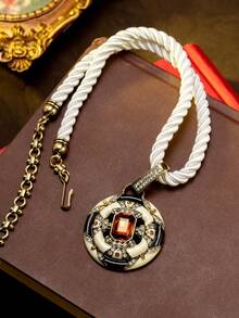 Một chiếc vòng cổ mặt dây chuyền hình tròn bằng men sứ kiểu cổ điển, mạ vàng, đính đá pha lê màu cam đỏ hình khối lập phương, phối màu đen trắng tương phản, dây bện màu trắng, thích hợp cho các dịp trang trọng như dạ hội, đám cưới, tiệc theo chủ đề cổ điển và đi làm hàng ngày, một phụ kiện bắt mắt tạo nên không khí thanh lịch thời trung cổ. - Nhiều màu - Xem 2