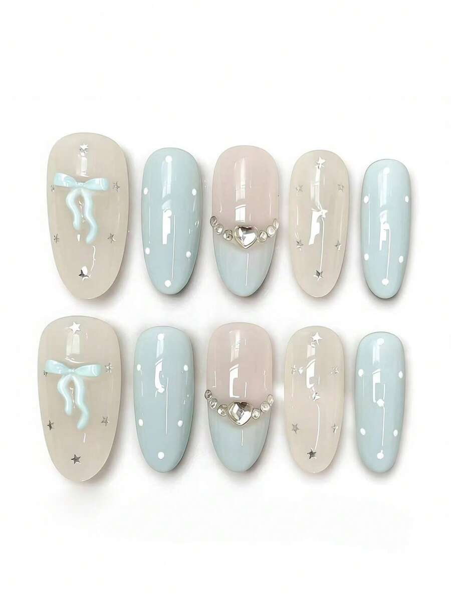 Bộ 10 móng tay mang tên Cyan Bow Star Diamond. Bộ móng này có sự kết hợp nhẹ nhàng giữa tông màu nude sữa, xanh băng giá và hồng phấn, cùng với họa tiết nơ màu xanh lam 3D, điểm nhấn ngôi sao bạc và chi tiết kim cương hình trái tim. Lớp sơn bóng bắt sáng như những chiếc nơ và ngôi sao màu xanh lam lấp lánh ánh kim cương, tạo nên một vẻ ngọt ngào, mộng mơ. - Màu xanh nhạt - Xem 1