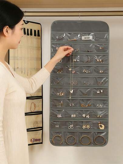 1 hộp đựng trang sức cuộn hai mặt bằng kim loại có móc, có thể treo trong tủ quần áo, trên tường hoặc cửa để đựng bông tai, dây chuyền, nhẫn và các loại trang sức khác.