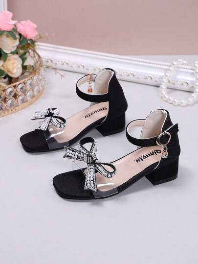 黑色粗跟凉鞋一双，柔软舒适的透明PU材质，饰以闪亮水钻搭扣和珍珠蝴蝶结，圆头露趾设计，3厘米坡跟增高防滑，时尚优雅的公主风高跟凉鞋，适合日常、度假、节日、派对、校园穿着，春夏新品。