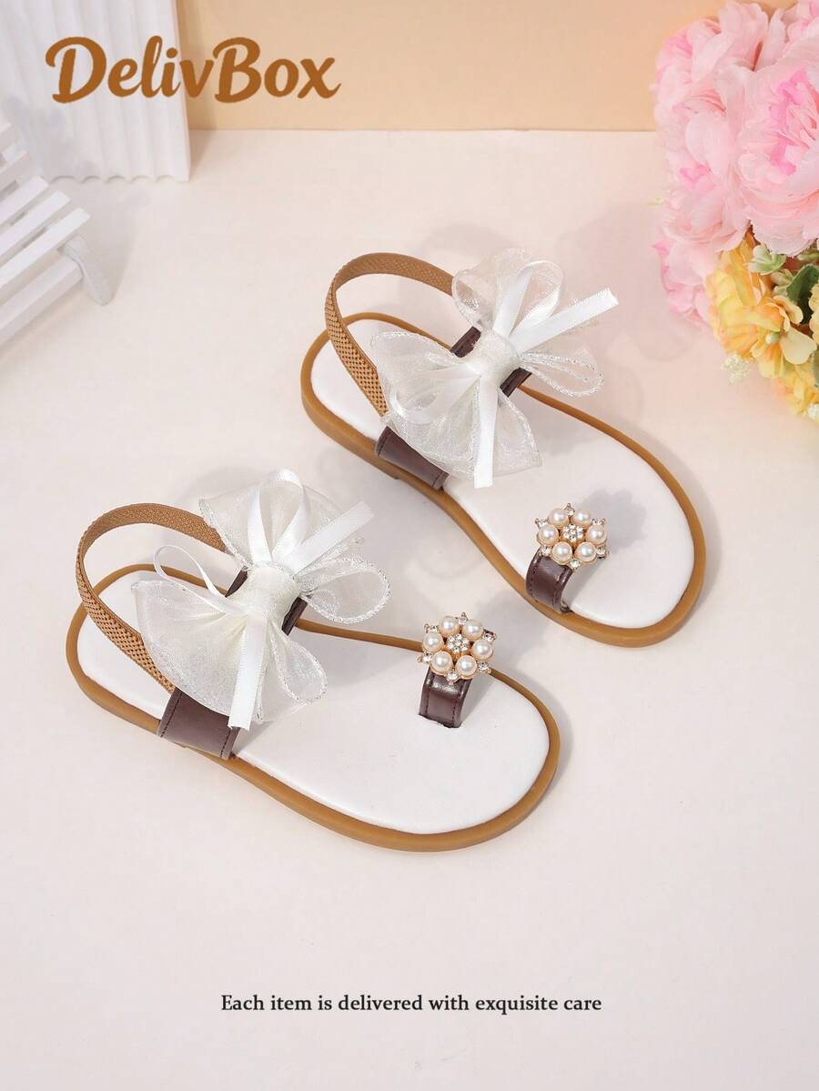 1 đôi dép xăng đan cho bé gái, trang trí nơ lưới và ngọc trai, chất liệu da PU, thoải mái khi xỏ, thiết kế cổ thấp, quai thun (quấn quanh mu bàn chân), kiểu đế bằng, mang đến vẻ ngọt ngào như công chúa, phù hợp cho các bữa tiệc mùa hè và mang hàng ngày. - màu nâu - Xem 1