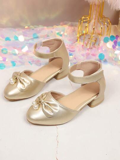 Giày sandal cao gót màu vàng đồng cho bé gái, chất liệu da ánh ngọc trai cao cấp, điểm nhấn là nơ ngọc trai, thiết kế quai hậu cổ điển, mũi nhọn, đế dày chống trơn trượt, kiểu dáng công chúa thời trang dễ thương, thanh lịch, phù hợp cho bé gái từ 3-15 tuổi, thích hợp mang hàng ngày, đi biển, nghỉ lễ, dự tiệc, mẫu mới mùa xuân/hè.