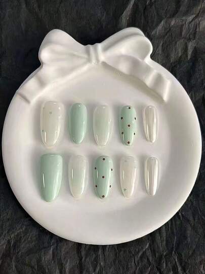 10片纯手工制作的中号椭圆形美甲贴片，以奶油白和薄荷绿为底色，融合了金属光泽、波点和星星元素，呈现出柔和可爱又不失活力、清新舒缓的美甲效果。这款温柔优雅的美甲贴片适合女士和女孩在春夏秋冬的各种节日、派对和日常生活中使用。