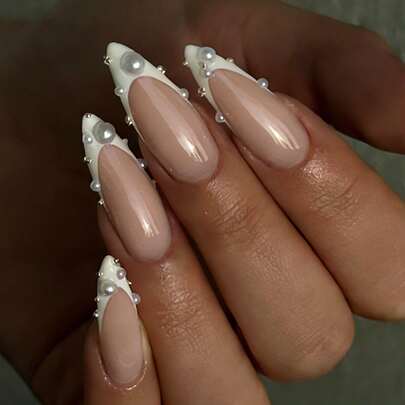 Bộ móng giả dài, nhọn màu trắng ngọc trai nude, 24 chiếc. Móng có lớp nền màu nude trong suốt được điểm xuyết bằng ngọc trai 3D và đá pha lê kim loại. Kiểu móng tay cô dâu tinh tế, thanh lịch, hoàn hảo cho đám cưới, hẹn hò và sử dụng hàng ngày. Những bộ móng giả thủ công này có thể tháo rời và tái sử dụng.