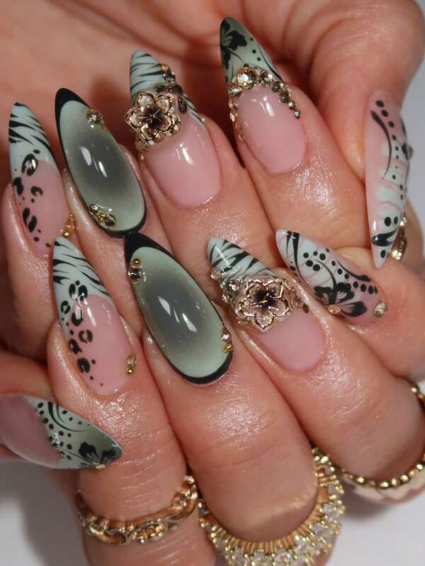 24 faux ongles en amande avec effet de peinture à l'encre, ornements floraux métalliques, incrustations de strass et base dégradée noir, blanc, gris et rose, créant un style luxueux et sexy