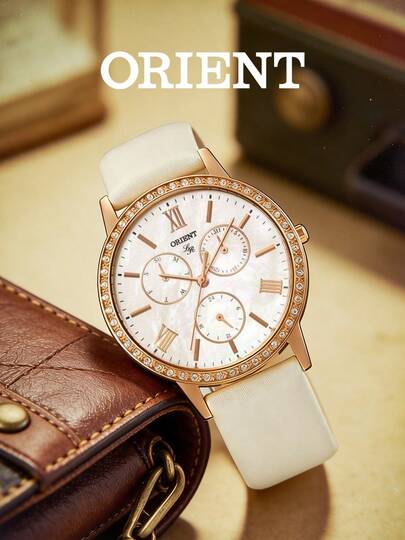 Orient Đồng hồ nữ, mặt số khảm xà cừ tự nhiên và viền vàng hồng đính kim cương. Thiết kế ba mặt số đa chức năng kết hợp cả vẻ đẹp và tính thực dụng. Dây đeo bằng da màu kem toát lên vẻ thanh lịch cổ điển.