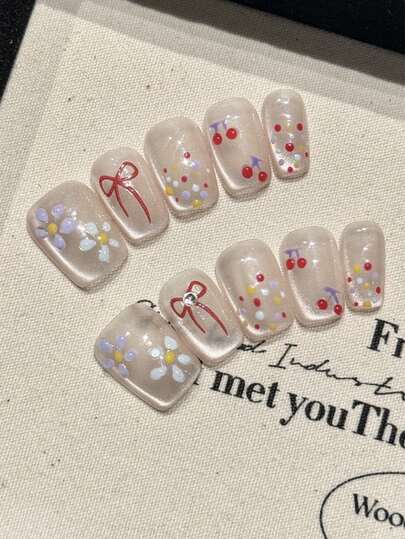 10片纯手工制作的按压式美甲，短款方形美甲，透明猫眼底，手绘小碎花图案，彩色波点和红色蝴蝶结，搭配小钻石装饰，细节丰富而不杂乱。温柔优雅可爱的美甲，适合女士和女孩春夏秋冬各种节日派对和日常佩戴。