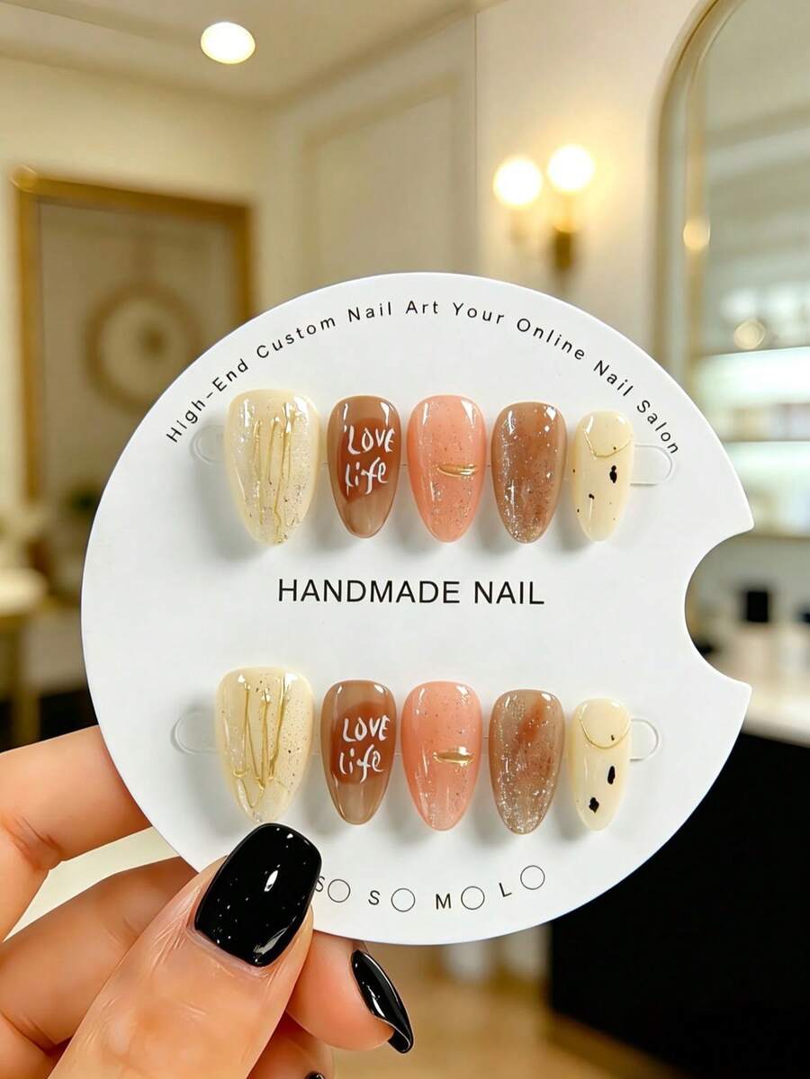 Bộ 10 móng tay giả hình hạnh nhân thủ công, có màu nâu ombre ấm áp, điểm xuyết những đường kẻ vàng tinh tế và các chấm đen nhỏ li ti, khắc chữ "LOVE Life". Những bộ móng tối giản nhưng thanh lịch này phù hợp với cả phụ nữ và bé gái, hoàn hảo cho các bữa tiệc, đám cưới và sử dụng hàng ngày. Sản phẩm đi kèm bộ dụng cụ. - Nhiều màu - Xem 1