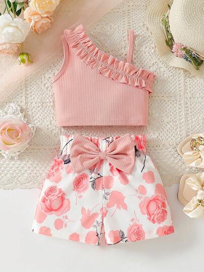 Bộ đồ 2 món cho bé gái mùa hè, gồm áo hai dây không tay xếp ly và quần short in hoa thắt nơ, thích hợp mặc ngoài trời.