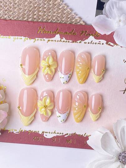 10片手工制作的杏仁形美甲贴片，黄色法式美甲风格，饰以白色蕾丝花边、黄色小花、渐变水波纹图案，食指上还有精致的手工雕刻设计，整体呈黄色。夏季必备单品。适合女孩和女士，易于佩戴和卸除，采用按压式美甲设计。