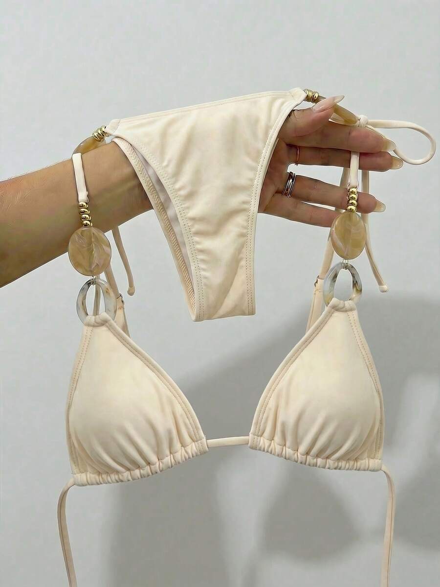 Bộ bikini hai mảnh thời trang dành cho nữ với thiết kế hở lưng buộc dây, điểm nhấn là những vòng hạt cườm và quần bikini buộc dây bên hông, thích hợp cho kỳ nghỉ hè trên bãi biển. - Màu be - Xem 1