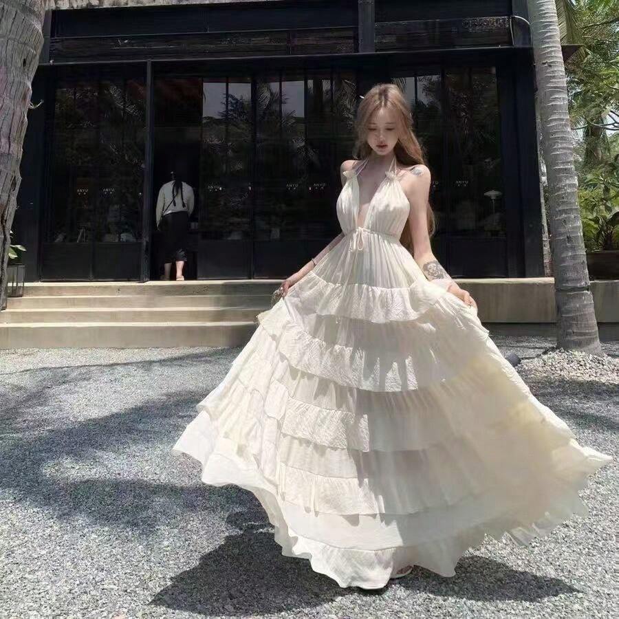 La mujer cuelga un vestido largo con una capa de pastel junto a una hoja de volantes de cuello V profundo. - Blanco - Ver 1