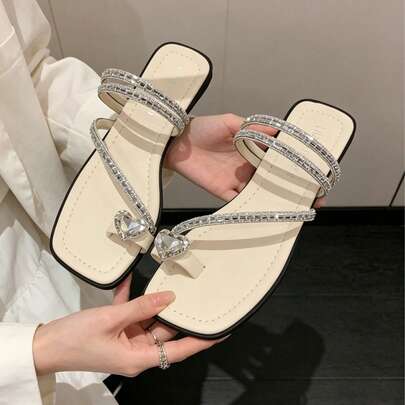 夏季最新系列主打奢华闪耀、功能多样且尺码宽松的水晶装饰中底鞋，适合大码身材。这款鞋饰有心形钻石点缀、露趾设计以及米色平底，是母亲节和情人节的理想礼物。它用途广泛，适合通勤、约会、购物、公寓生活、度假、海滩活动或派对等各种场合。