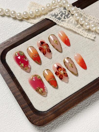 10 pièces/set Faux ongles faits à la main en forme d'amande, couleurs nude, rouge et orange avec bord français, pointes d'ongles Gel-X avec fleur 3D orange, mélange de rougeur orange et rose, ongles incrustés de perles et d'ornements métalliques. Convient aux femmes et aux filles, pour les fêtes et le port quotidien pour rehausser votre style de mode ! Comprend 1 pièce de gel de gelée et 1 pièce de lime à ongles. Excellent cadeau pour les fournitures pour ongles des dames, le Nail Art Salon