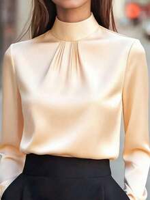 Blusa de mujer de satén negro, con cuello alto, mangas largas y pliegues en el pecho.Su textura satinada le da un aire elegante y versátil, perfecta para usar en la oficina, eventos formales o looks casuales, durante todo el año. - Albaricoque - Ver 1