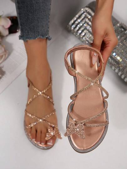 Sandal đế bằng mùa hè mới, kiểu dáng quai chéo, đính đá và nơ xinh xắn, thích hợp cho nữ.