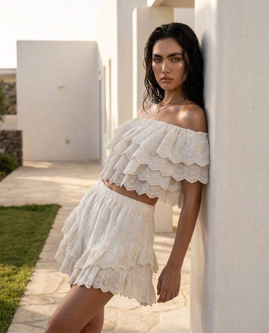 Rouah Zweistufiges Broderie Anglaise Crop Top mit Off-Shoulder Ausschnitt in Weiß. Genießen Sie sonnendurchflutete Tage mit diesem himmlischen weißen Broderie Anglaise Crop Top, das eine perfekte Harmonie aus Textur und verspieltem Design ist. Aus feinem Lochstickstoff gefertigt, verkörpert dieses Stück einen mühelosen Boho-Geist für Ihren nächsten Sommerurlaub. - Weiss - Übersicht 1