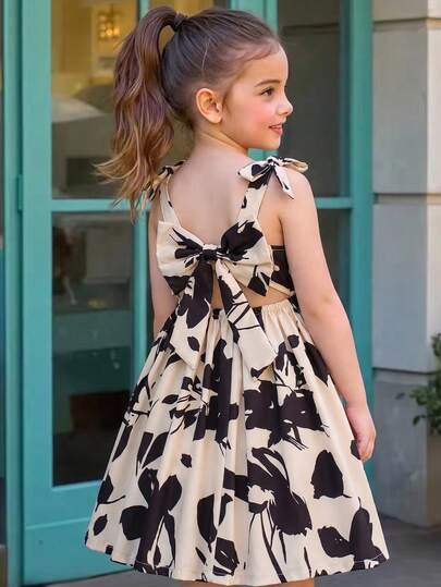 Đầm hai dây in họa tiết hình học cho bé gái, điểm nhấn là chiếc nơ lớn, kiểu dáng công chúa thanh lịch ôm sát.