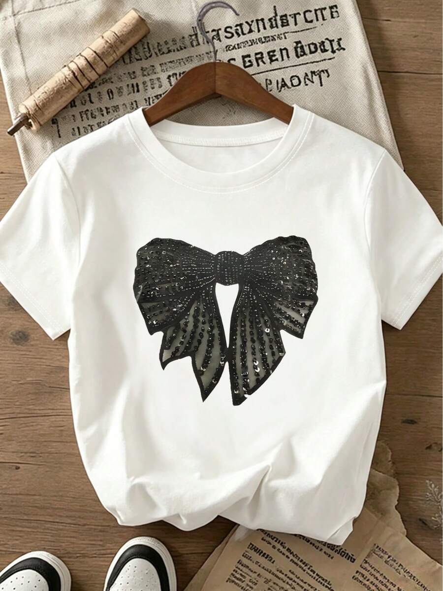 Camiseta feminina plus size casual com gola redonda, laço de lantejoulas e modelagem solta, ideal para encontros românticos. Disponível também em modelos estampados, manga curta e cor branca. Perfeita para o verão. Ideal para o Dia dos Namorados. - Branco - Ver 1
