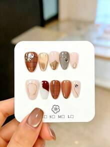 10片手工制作的杏仁形假指甲，饰以不对称金色镜面闪粉和不对称线条水钻，美观优雅，可拉长手指，提亮肤色。这款可重复使用的美甲饰品易于佩戴和卸除，适合女士日常佩戴、参加派对、婚礼、节日等场合。套装包含果冻胶、指甲锉和其他美甲工具。 - 摩卡棕 - 查看 13