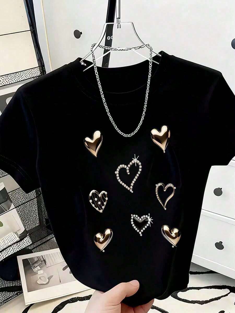 Esta camiseta holgada y transpirable presenta un diseño sencillo con corazones metálicos estampados y detalles de pedrería. Es una camiseta informal adecuada tanto para ocasiones festivas como para el uso diario. - Negro - Ver 1