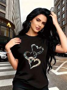 El epítome de "emoción y amor", esta camiseta de manga corta para mujer presenta un estampado de corazón metálico, moderno y a la moda, con un cuello redondo sencillo y un diseño casual versátil, adecuada para el ocio, viajes, vacaciones y otras actividades. - Negro - Ver 4