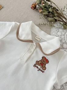 Bộ 2 món gồm áo polo trắng tay ngắn thêu hình gấu dễ thương cho bé gái và chân váy xếp ly màu nâu, thích hợp cho mùa hè. - trắng - Xem 3