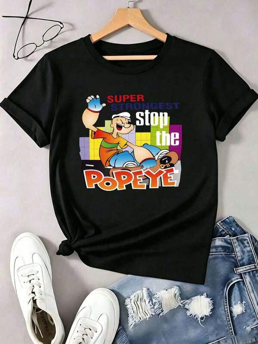 Playera negra de algodón para mujer con estampado de personaje de caricatura retro con texto "Super Strongest" y fondo de ciudad, estilo nostálgico y llamativo, ideal para uso diario, salidas casuales y looks de verano