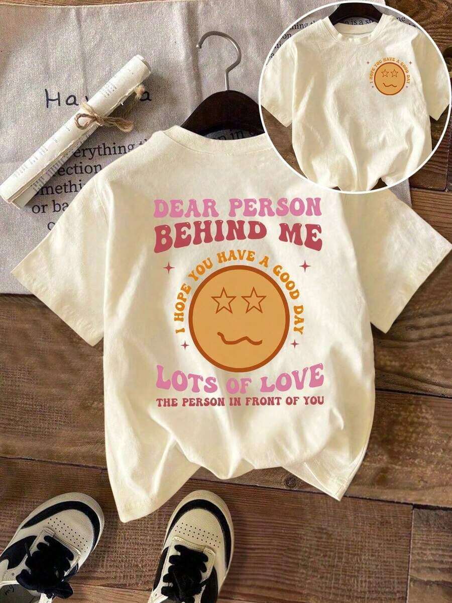 Camiseta de manga corta con cuello redondo y estampado a doble cara, que muestra una cara sonriente y el texto "QUERIDA PERSONA DETRÁS DE MÍ". - Albaricoque - Ver 1