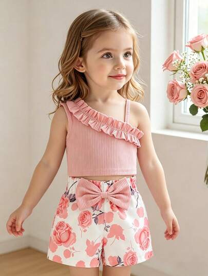 Bộ đồ 2 món cho bé gái mùa hè, gồm áo hai dây không tay xếp ly và quần short in hoa thắt nơ, thích hợp mặc ngoài trời.