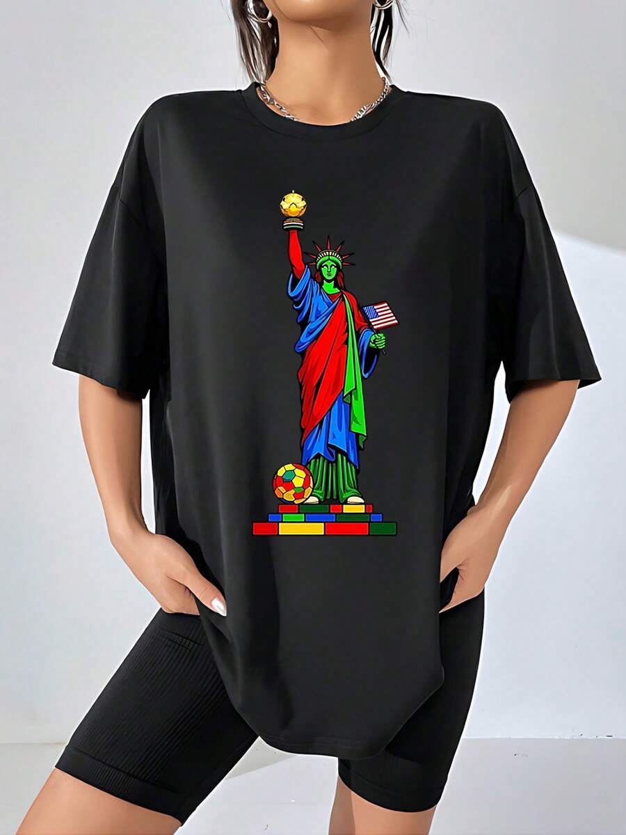 Figura colorida de la Estatua de la Libertad sosteniendo un balón dorado y una bandera de Estados Unidos sobre bloques multicolores que simbolizan unión y diversidad camiseta de mujer 100% algodón cómoda y moderna para uso casual - Negro - Ver 1