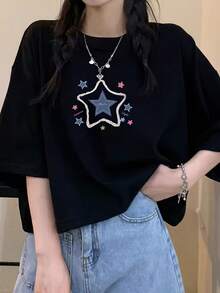 Una versátil camiseta para mujer que destaca por su llamativa estrella roja gigante y un divertido estampado de pequeñas estrellas coloridas. Hecho 100% de algodón, es un atuendo divertido y cómodo para ir de compras o reuniones informales. Camiseta unisex de manga corta y cuello redondo, estilo vintage urbano. - Negro - Ver 1