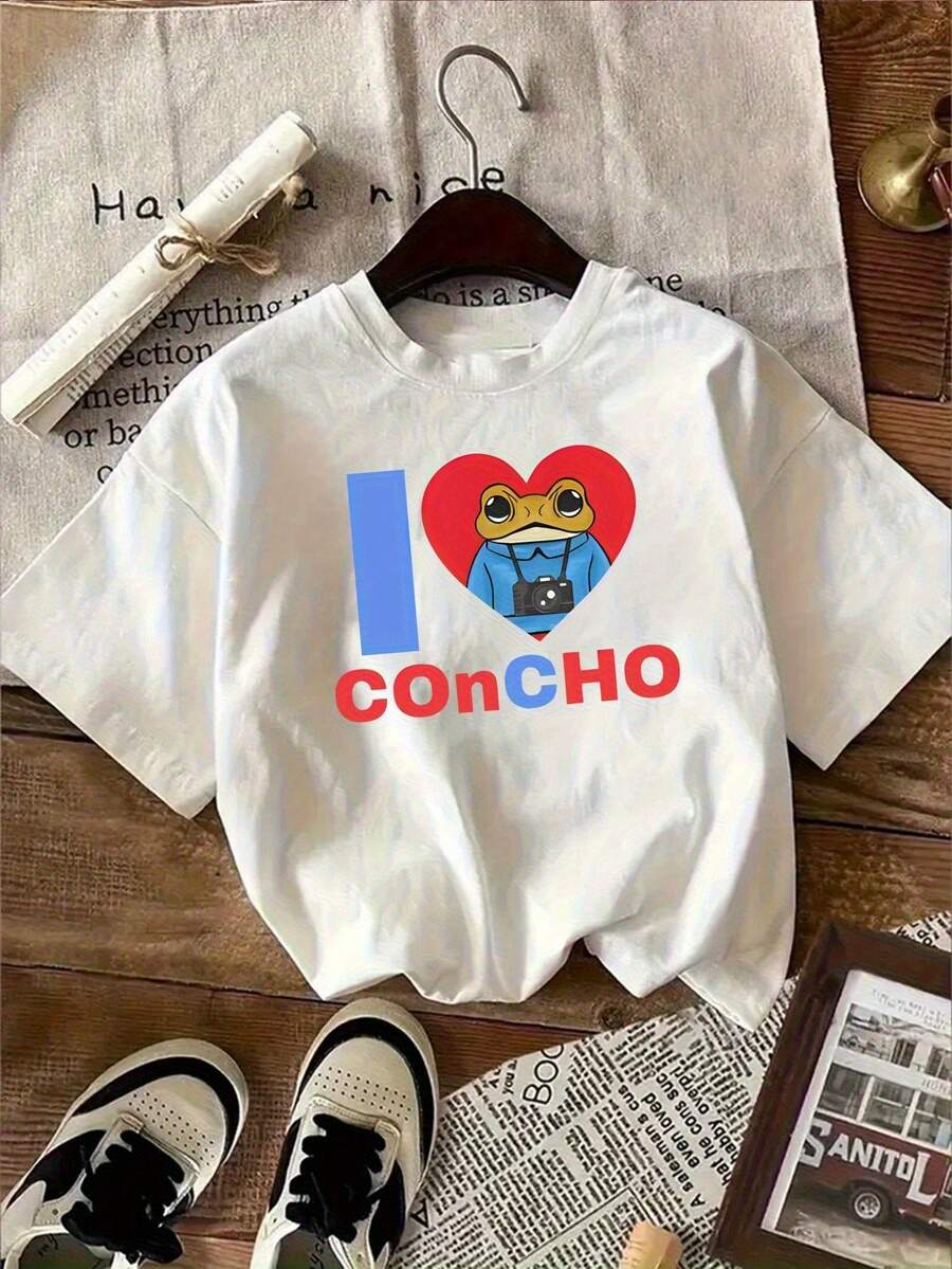 Camiseta Blanca con Divertido Diseño de Rana de Dibujos Animados Sosteniendo una Cámara y un Corazón Rojo, con la Palabra "Concho" - Estilo Casual Único, Perfecta para Amantes de la Fotografía y la Moda, Ideal para Verano y Actividades al Aire Libre, Camiseta Y2k - Blanco - Ver 1