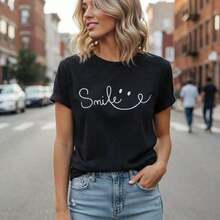 Camiseta de algodón con estampado gráfico de sonrisa para mujer, manga corta, cuello redondo, top casual, camiseta holgada para verano, disponible, camiseta básica suave y cómoda, blusa con estampado de letras a la moda, túnica femenina para uso diario. - Negro - Ver 1