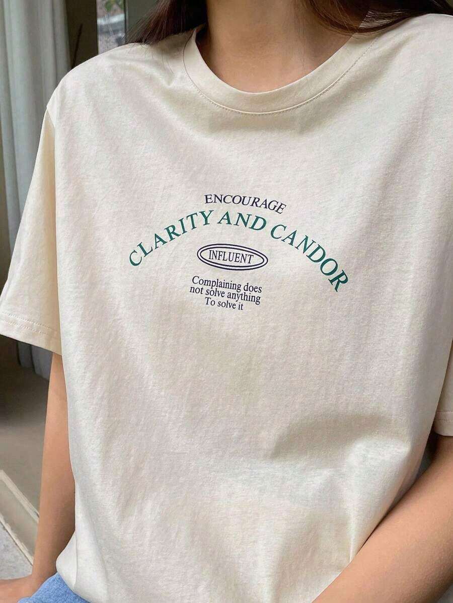 Una camiseta de manga corta para mujer con estilo retro americano, de corte holgado y con diseño estampado (los pantalones son solo para sugerencias de estilo). Esta pieza sencilla y elegante presenta un patrón de letras impresas con temática tropical, lo que la convierte en un elemento imprescindible para crear un look relajado de vacaciones, perfecto para ocasiones como el Día del Trabajo y el Día de la Independencia de México. - Beis - Ver 1