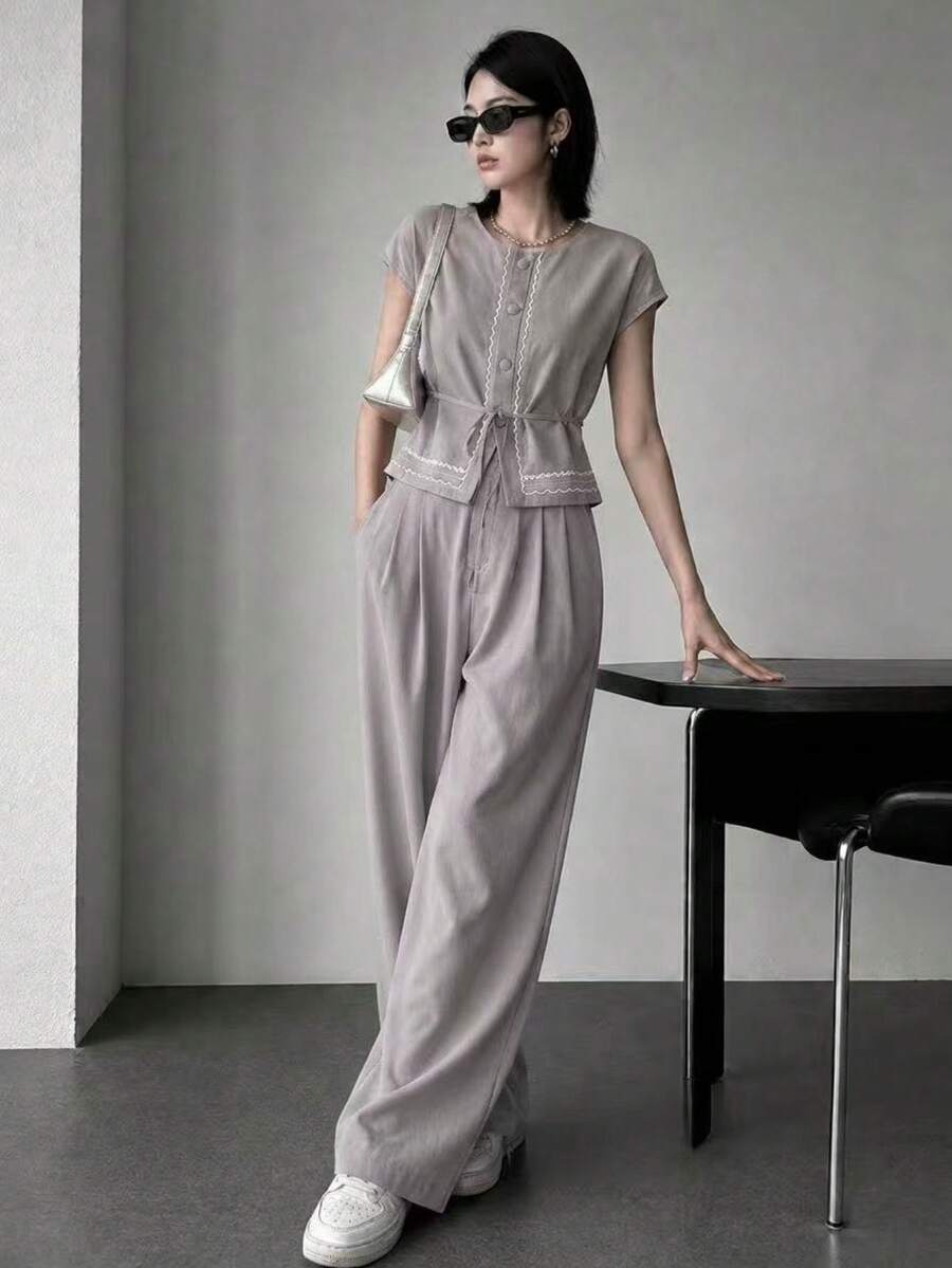 A&DD MODA, REF: AS1990 - Women's Set Consisting Of A Short-Sleeved Blouse And Pants. The Blouse Has A Round Neckline With Details And Buttons. The Pants Have A Straight Cut For A Slimming Effect. This Casual Yet Elegant Set Is Ideal For Special Occasions And Social Events, Creating A Complete And Sophisticated Look. - Xám - Xem 1