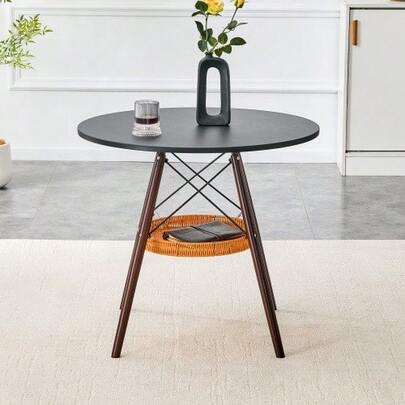 A Round Dining Table With A Diameter Of 80 Cm, A Tabletop Made Of Black MDF And Table Legs Made Of Walnut-Colored Solid Wood, Complemented By A Floating, Woven Storage Compartment.