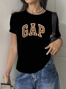 Letras grandes en relieve color naranja que expresan energía moderna y confianza juvenil sobre fondo oscuro creando un contraste vibrante y atractivo camisetas de mujer corte casual cómodo para uso diario - Negro - Ver 1