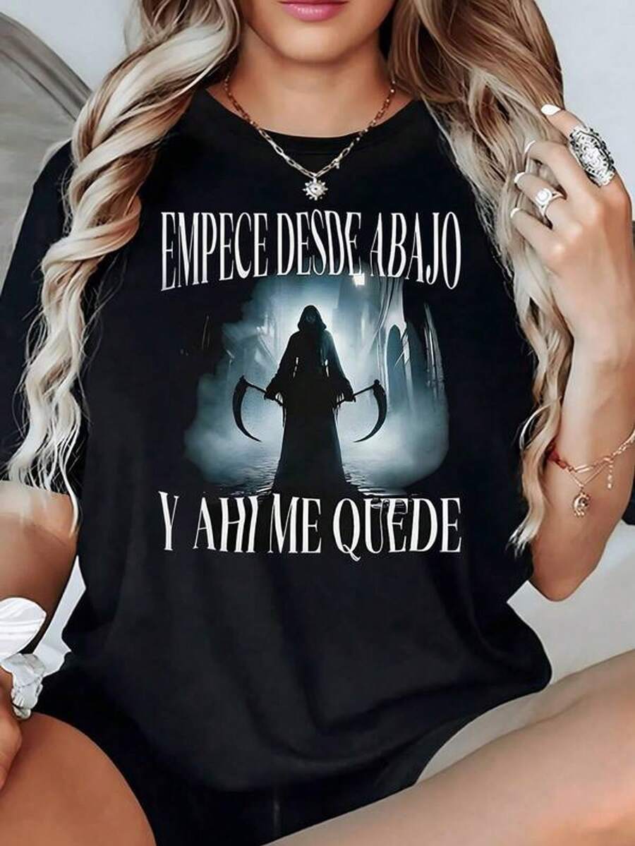 Figura sombría con capucha sosteniendo dos guada?as en un paisaje oscuro que refleja fortaleza y resiliencia camiseta de mujer 100% algodón 220g