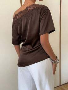 Elegante blusa de satén negro con escote asimétrico en el hombro y ribete de encaje.Esta camiseta de manga corta y bajo asimétrico presenta una silueta estilizadora y favorecedora, convirtiéndola en una opción elegante y versátil tanto para el - Marrón - Ver 2