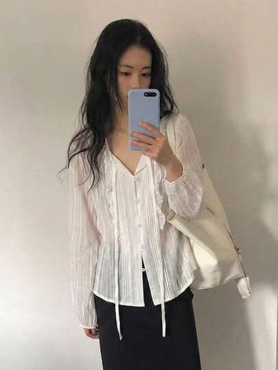 Áo kiểu dáng thanh lịch, đa năng, cổ bèo nhún họa tiết hoa, tay dài xếp ly, thắt nơ, màu trắng.