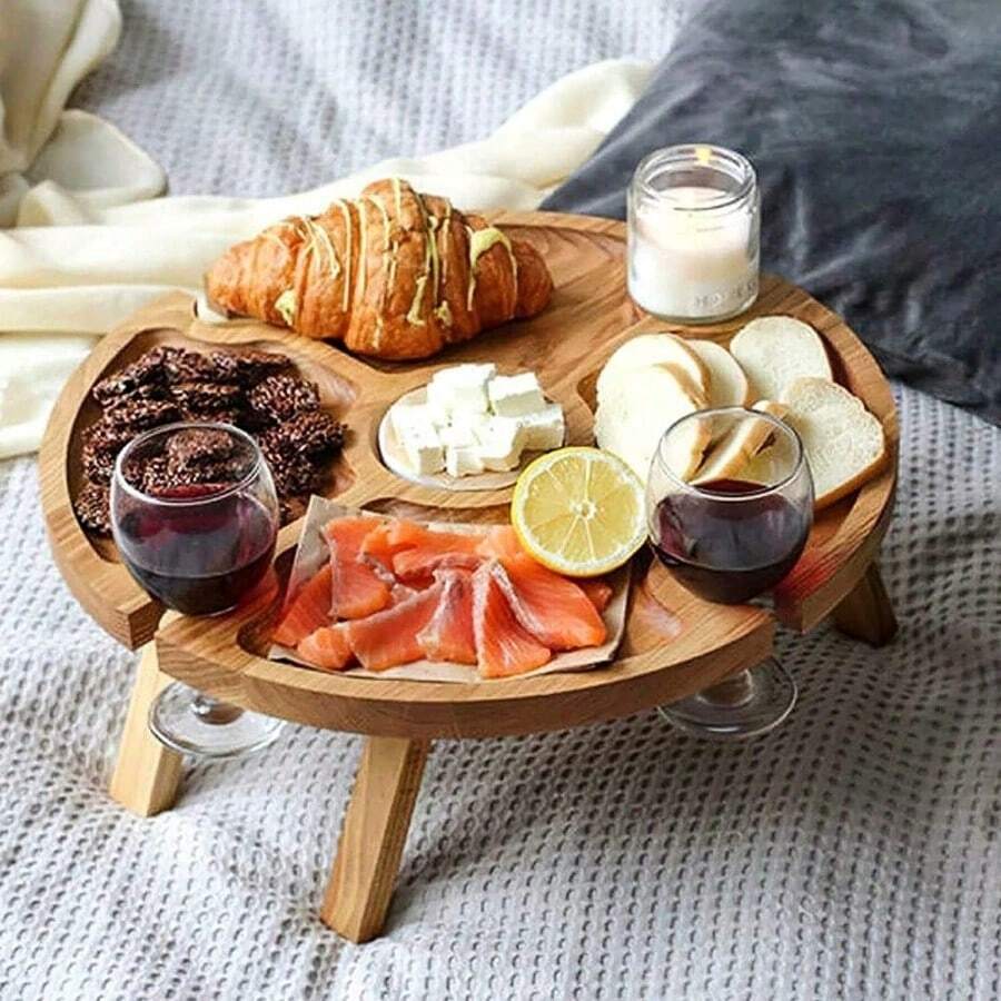 1 khay ăn nhẹ gấp gọn ngoài trời, kiểu dáng gỗ tự nhiên, hình tròn, có vách ngăn và rãnh đựng cốc chân đế cao.