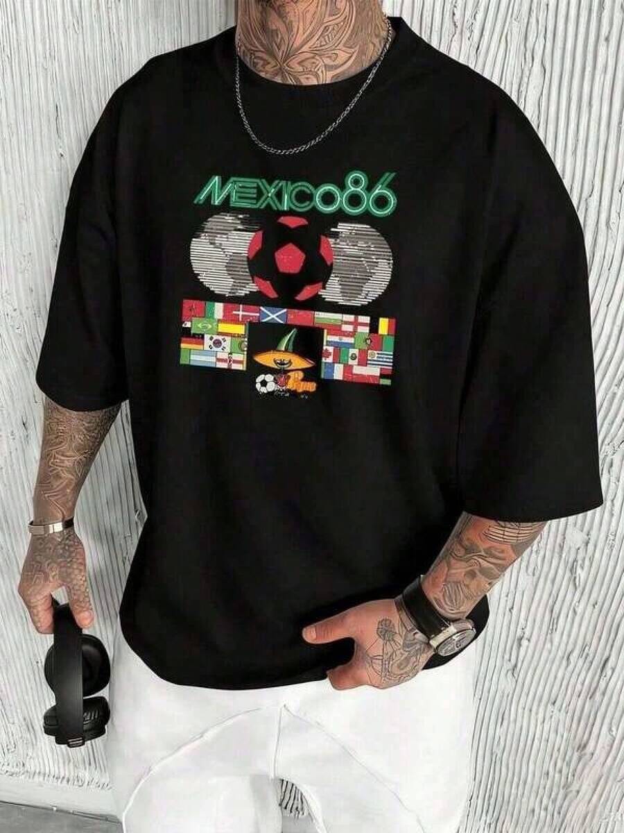 Camiseta de manga corta con estampado gráfico TeesRepresenta el espíritu del Mundial México 86 con agua mascota Pique y el balón de fútbol adornado con banderas de varios países simbolizando la unidad y la pasión fútbolístico es un diseño retro y festivo camiseta de hombre 100% algodón. Camisa de mujer 100% algodón, casual 100% algodón. - Negro - Ver 1