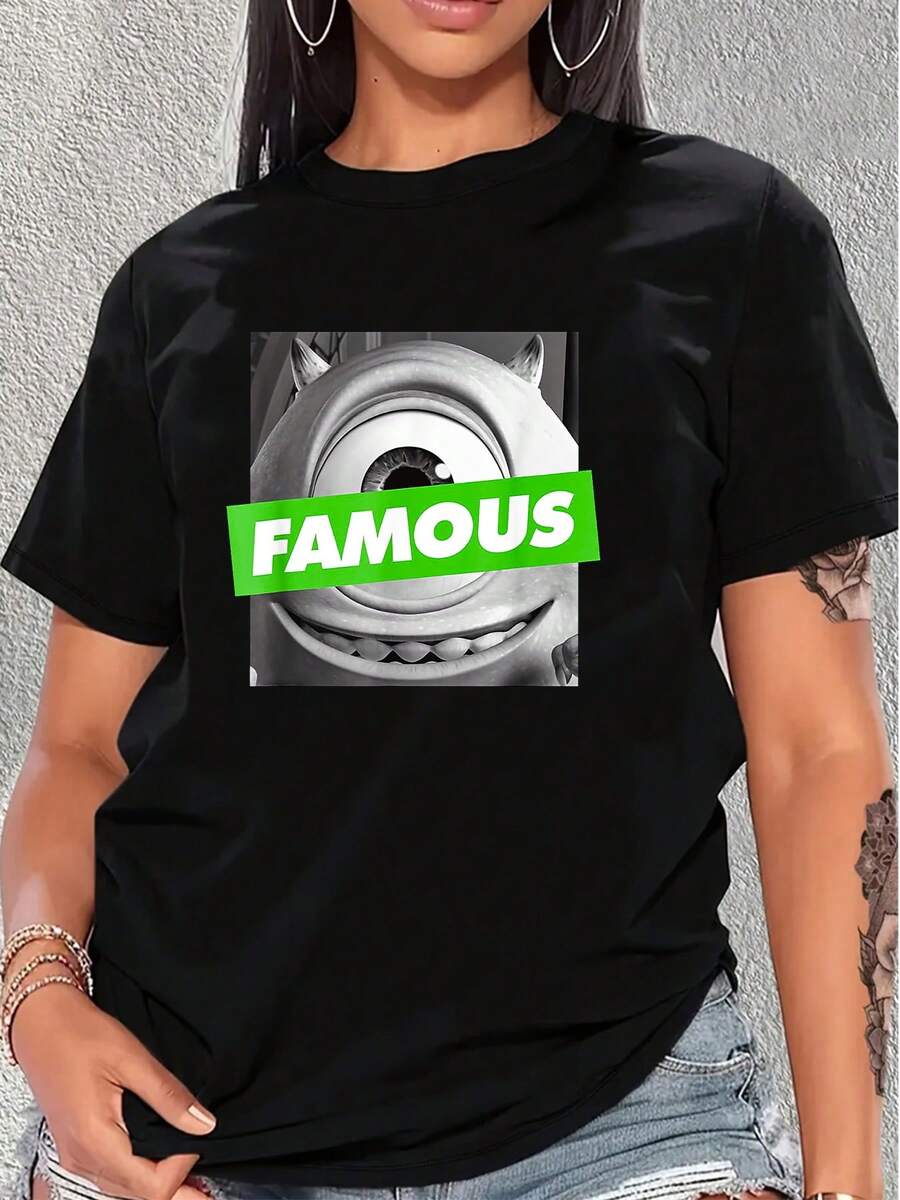Gráfico con un gran ojo central rodeado de formas suaves que simboliza la curiosidad y la confianza, acompañado de la palabra FAMOUS en color verde brillante que representa energía y actitud moderna camiseta de mujer cómoda y casual para uso diario - Negro - Ver 1