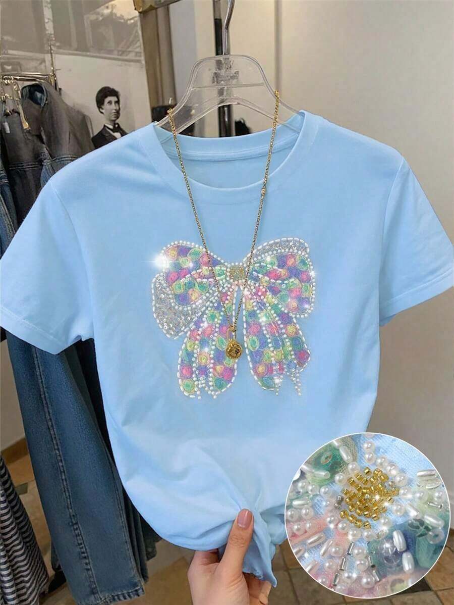 Camiseta de mujer de manga corta y cuello redondo con bordado de lentejuelas en forma de lazo, 56% algodón, estilo minimalista de moda, regalo para amigos - Celeste - Ver 1