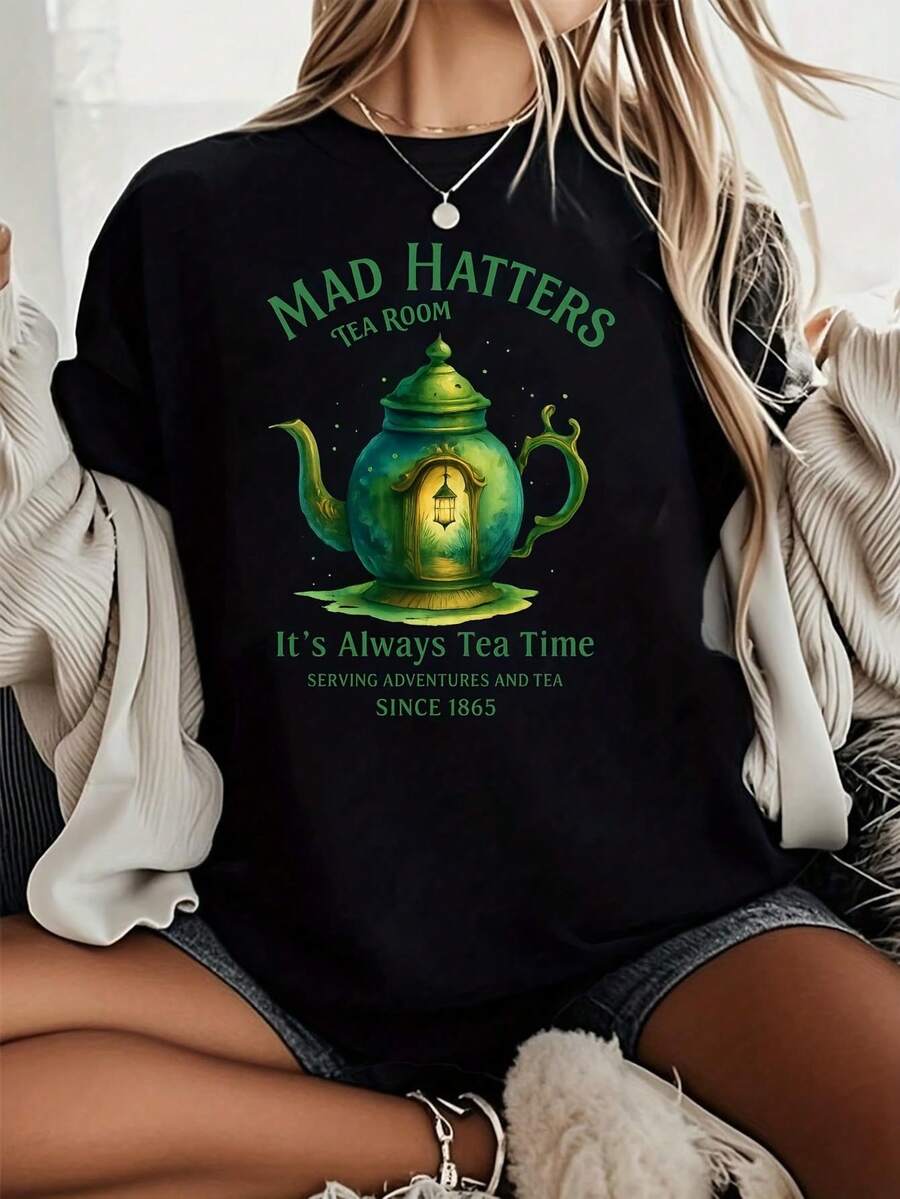 Camiseta Gráfica Negra para Mujer - Con Diseño de Tetera Verde y Linterna, Texto 'MAD HATTERS' y 'It's Always Tea Time' - Camiseta Casual de Verano para Amantes del Té y Aventureros. Con un corte nítido y estilizado, esta prenda crea un look limpio y vibrante al usarla.Su silueta holgada pero favorecedora se adapta a todo tipo de cuerpos, ofreciendo un estilo que es a la vez casual y con un toque de elegancia. - Negro - Ver 1